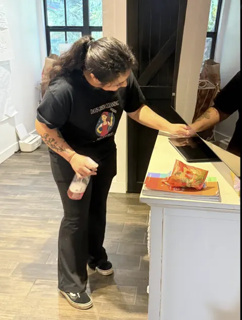 A Davis Green crew member in a logo tee cleaning a counter